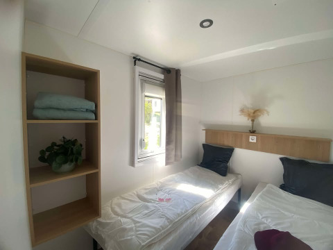 Lyst værelse med to enkeltsenge, vindue, åbne hylder og minimalistisk indretning på Cottage i Frankreich.