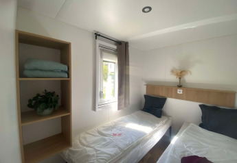 Lyst værelse med to enkeltsenge, vindue, åbne hylder og minimalistisk indretning på Cottage i Frankreich.