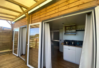 Terrazza in legno e porte a vetro aperte su una cucina moderna in un cottage presso Domaine Seasonova Saâne et Mer, Francia