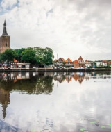 Veduta di Hasselt, Overijssel, Paesi Bassi, con la storica torre della città riflessa nell’acqua tranquilla.