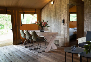 Innenraum eines Luxus-Safari-Glampingzeltes mit Esstisch und Blumen in Glampingtent Lina, Niederlande.