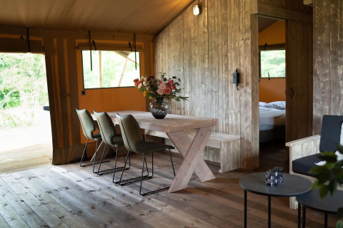 Interieur van een luxe safari glampingtent met eettafel en bloemen bij Glampingtent Lina, Nederland.