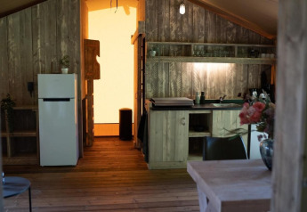 Interior de Glampingtent Lina en Glamping Franse Peer, Países Bajos, con cocina y decoración de madera.