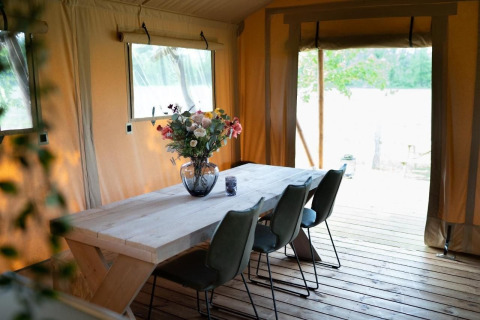Essbereich mit Holztisch und Blumen in Safari-Zelt Glampingtent Lina, Glamping Franse Peer, Niederlande.