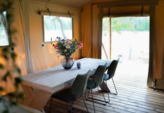 Essbereich mit Holztisch und Blumen in Safari-Zelt Glampingtent Lina, Glamping Franse Peer, Niederlande.