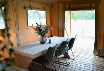 Essbereich mit Holztisch und Blumen in Safari-Zelt Glampingtent Lina, Glamping Franse Peer, Niederlande.