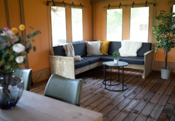 Salon confortable dans la Glampingtent Lina au Glamping Franse Peer, Pays-Bas, avec canapé et plantes.