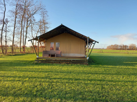 Ein Bild vom Safari-Zelt Glampingtent Joukje, gelegen auf einer grünen Wiese im ländlichen Raum.