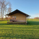 Afbeelding van Glampingtent Joukje, een safaritent op een groen grasveld met bomen en blauwe lucht.
