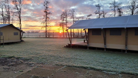 Lever du soleil à Glamping Franse Peer, Overijssel, Pays-Bas, avec tentes et gazon givré du matin.