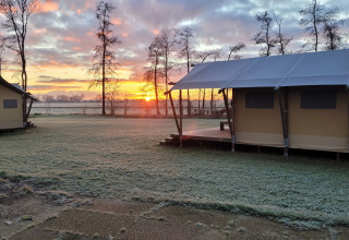 Lever du soleil à Glamping Franse Peer, Overijssel, Pays-Bas, avec tentes et gazon givré du matin.