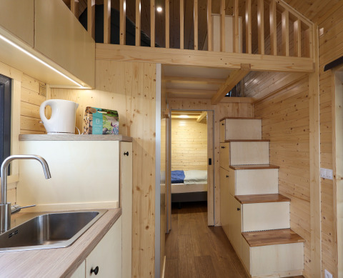 Interior de una tiny house en Camping Vinkenhof, Países Bajos, con madera y cocina pequeña.