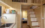 Interior of a tiny house at Camping Vinkenhof in the Netherlands with wood paneling and loft.