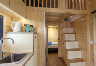 Interior de una tiny house en Camping Vinkenhof, Países Bajos, con madera y cocina pequeña.