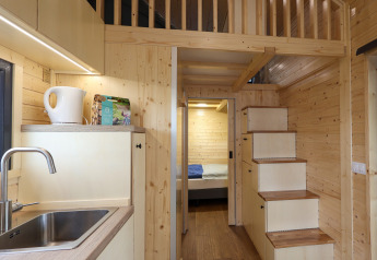 Interiør af et lille hus på Camping Vinkenhof i Holland med trævægge, tekøkken og hems.