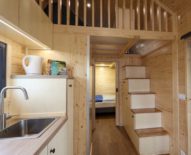 Interior of a tiny house at Camping Vinkenhof in the Netherlands with wood paneling and loft.