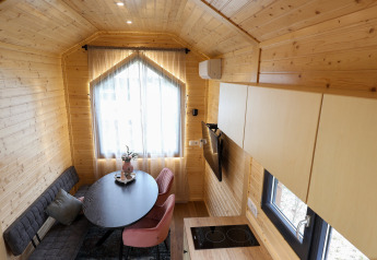 Cozy, modern tiny house interior at Camping Vinkenhof in the Netherlands, featuring wood paneling and seating.