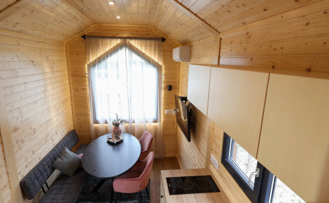 Cozy, modern tiny house interior at Camping Vinkenhof in the Netherlands, featuring wood paneling and seating.