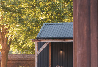 Cuatro personas sentadas afuera en una mesa de picnic junto a una tiny house en Camping Vinkenhof, Holanda.
