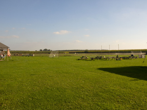 Campo verde de parque vacacional con bancos de picnic, porterías y cielo despejado en Brabantse Hei, Países Bajos.