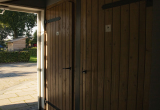 La luz del sol entra por una puerta de madera abierta en Feather Down De Brabantse Hei, parque vacacional en Noord-Brabant.