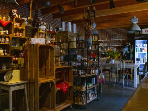 Tienda acogedora con estanterías de madera, nevera y mesas en Feather Down De Brabantse Hei, Países Bajos.