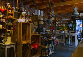 Indretning af en hyggelig landbutik med træhylder, køleskab og borde hos Feather Down De Brabantse Hei.