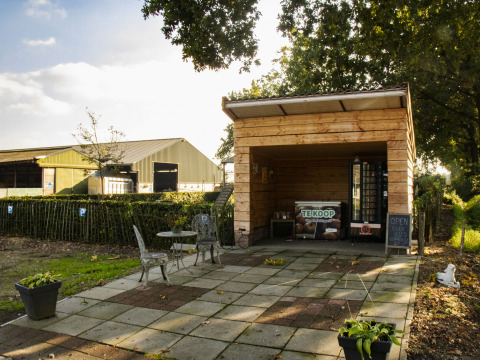 Outdoor farm shop with seating area at Feather Down De Brabantse Hei holiday park, North-Brabant, Netherlands.