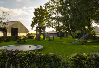 Børnevenlig legeplads med rutsjebane, trampolin og picnicborde i en grøn feriepark i Nord-Brabant, Holland.