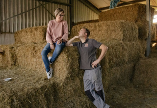 Twee personen kletsen op hooibalen bij Feather Down De Brabantse Hei, Noord-Brabant, Nederland.