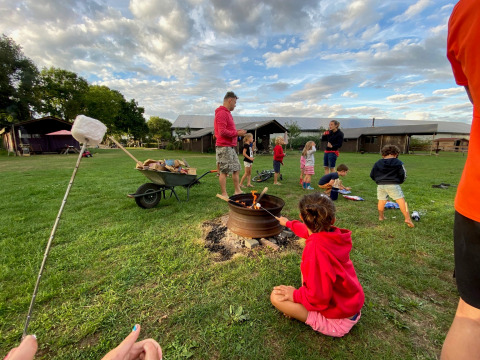 Kinderen en volwassenen roosteren marshmallows aan het kampvuur op Feather Down De Brabantse Hei, Noord-Brabant.