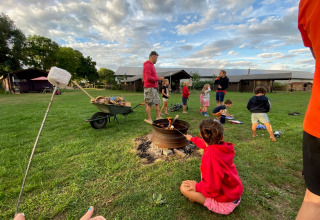 Familien rösten Marshmallows am Lagerfeuer im Feather Down De Brabantse Hei Ferienpark in Nordbrabant.