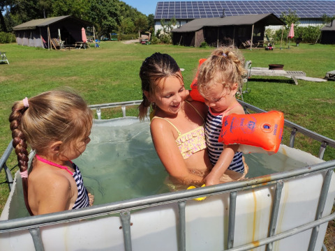 Niños jugando en una pequeña piscina en Feather Down De Brabantse Hei, un parque vacacional en Brabante Septentrional, Países Bajos.