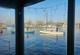 Vue sur des bateaux et la marina du parc de vacances Marina Heeg en Frise, Pays-Bas, à travers une fenêtre.
