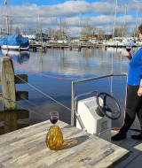 Una mujer disfruta una copa de vino junto al agua con vista a botes en Marina Heeg, Frisia, Países Bajos.
