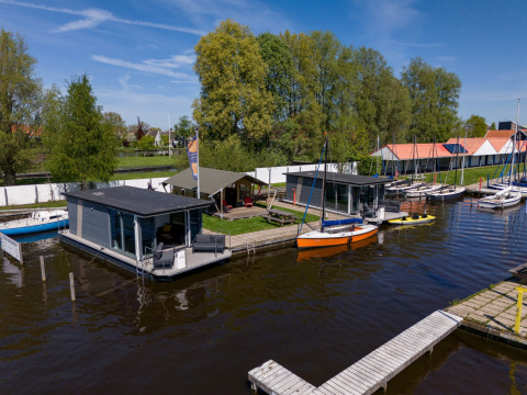 Casas flotantes y barcos en el parque vacacional Marina Heeg en Frisia, Países Bajos, rodeados de naturaleza.