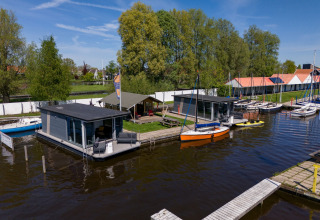 Schwimmende Ferienhäuser und Boote am Marina Heeg Ferienpark in Friesland, Niederlande, mit Natur.