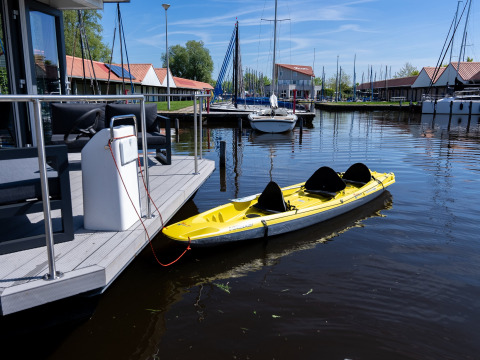 Gul kajak fastgjort til en flydebro ved Marina Heeg feriepark i Friesland, Holland, med sejlbåde bagved.