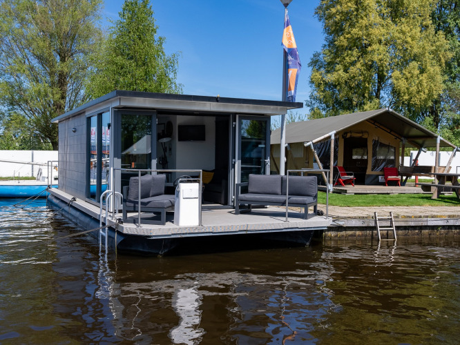 Drijvend vakantiehuis en tent bij vakantiepark Marina Heeg in Friesland, Nederland, aan het water.