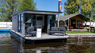Floating holiday home and tent at Marina Heeg holiday park in Friesland, Netherlands, by the water.