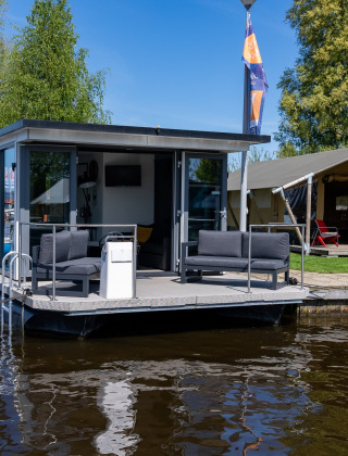 Casa flotante y tienda en el parque vacacional Marina Heeg en Frisia, Países Bajos, junto al agua.