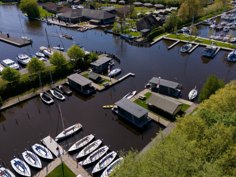Vista aérea de Marina Heeg, parque vacacional en Frisia, Países Bajos, con barcos y casas en la orilla.