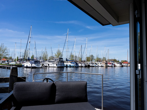 Vista de yates y veleros en Marina Heeg, parque vacacional en Frisia, Países Bajos, desde una terraza soleada.