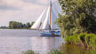 Sailboat on the lake at Marina Heeg, a holiday park in Friesland, Netherlands, surrounded by greenery.