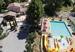 Luftfoto af Flower Camping La Rivière med swimmingpool, vandrutsjebaner og solstole i Provence, Frankrig.