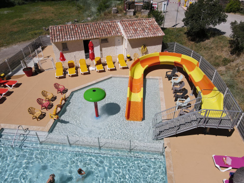 Vista dall'alto dell’area piscina con scivolo colorato e lettini presso il Flower Camping La Rivière, Francia.