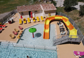 Aerial view of pool area with colorful slide and sun loungers at Flower Camping La Rivière in France.