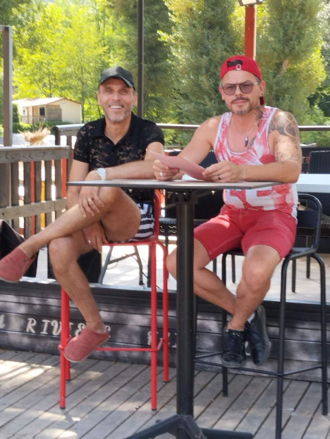 Dos hombres sentados en una mesa al aire libre en Flower Camping La Rivière, Provenza-Alpes-Costa Azul, Francia.