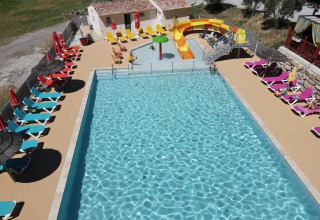 Schwimmbad mit Liegestühlen, Wasserrutsche und Sonnenschirmen im Flower Camping La Rivière, Provence.
