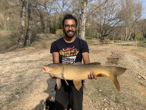 Uomo sorridente con un grosso pesce a Flower Camping La Rivière in Provenza-Alpi-Costa Azzurra, Francia.